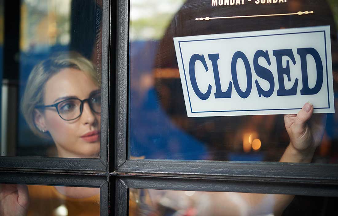 Business owner switching the sign on their door to "Closed".