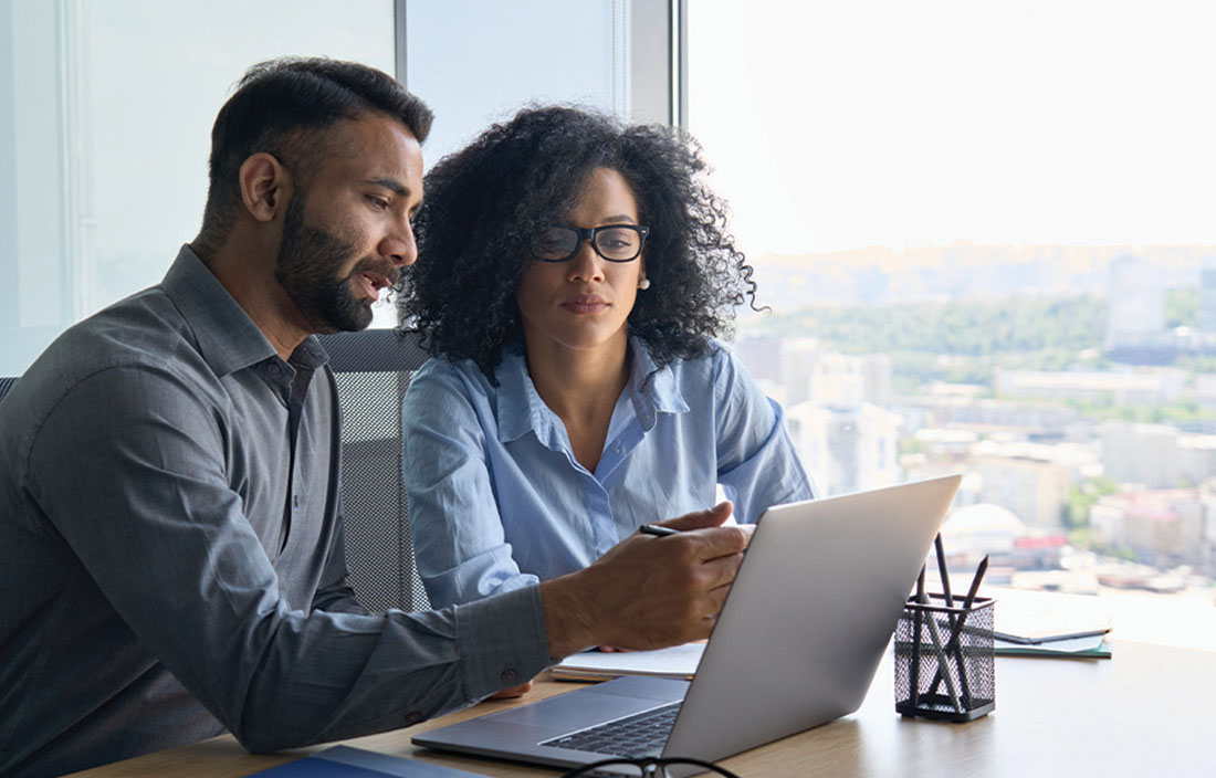 Two people sitting at a desk look at Gross Domestic Product data on the computer