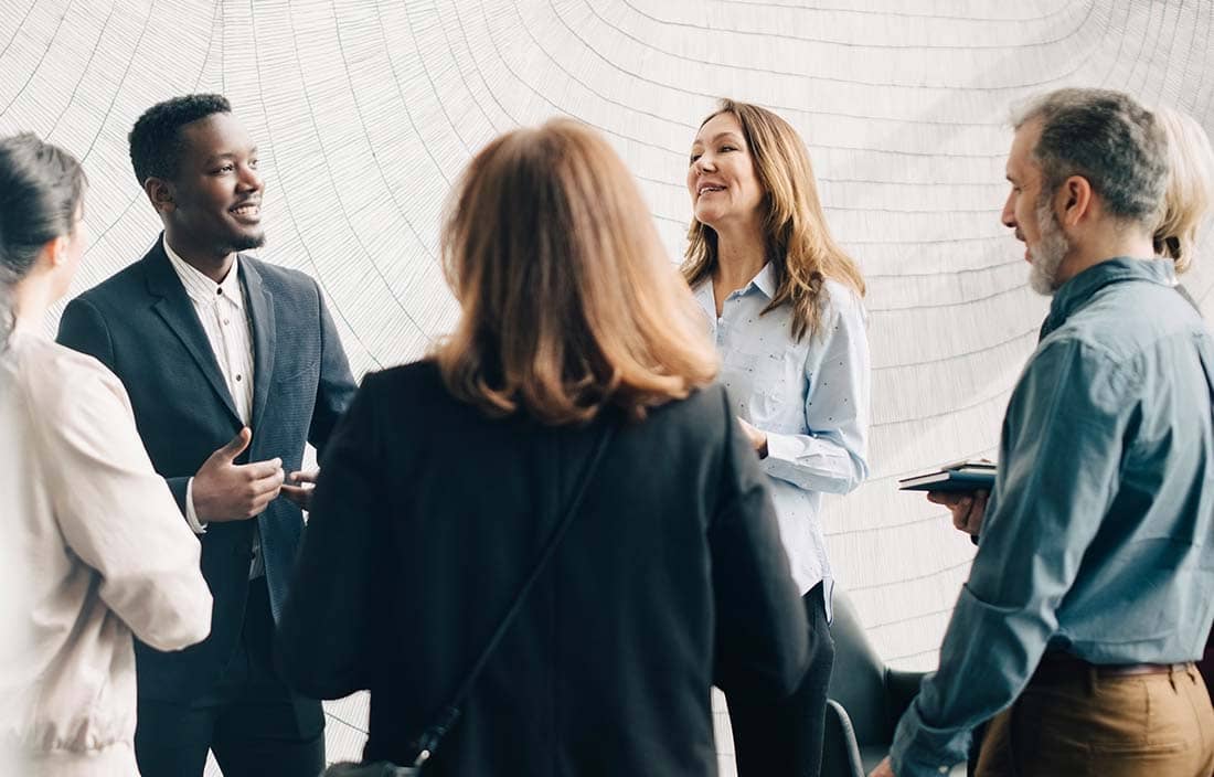 A group of racially diverse business professionals talking and smiling.