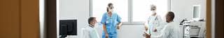 Group of doctors and nurses talking in hospital room.