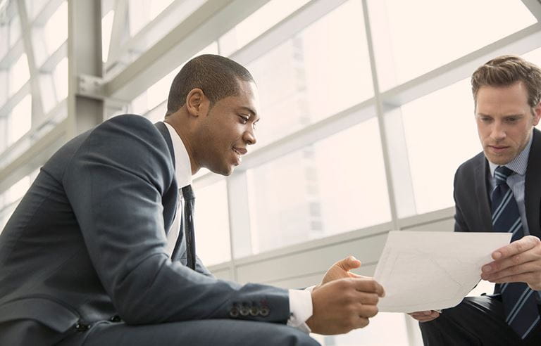 Two men in suits in an office meeting.