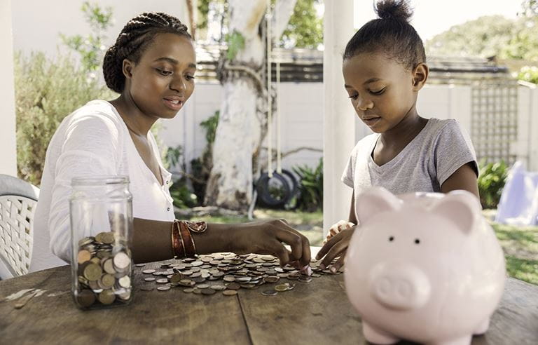 Image of mother and daughter counting coins from piggy bank