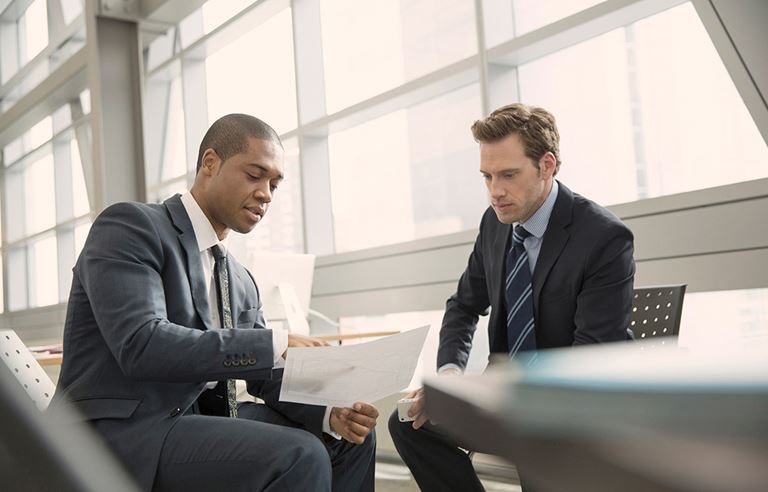 Two business men sitting and discussing a report