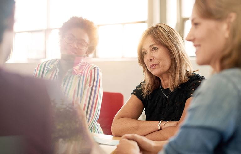 Three women sitting and listening to someone speak