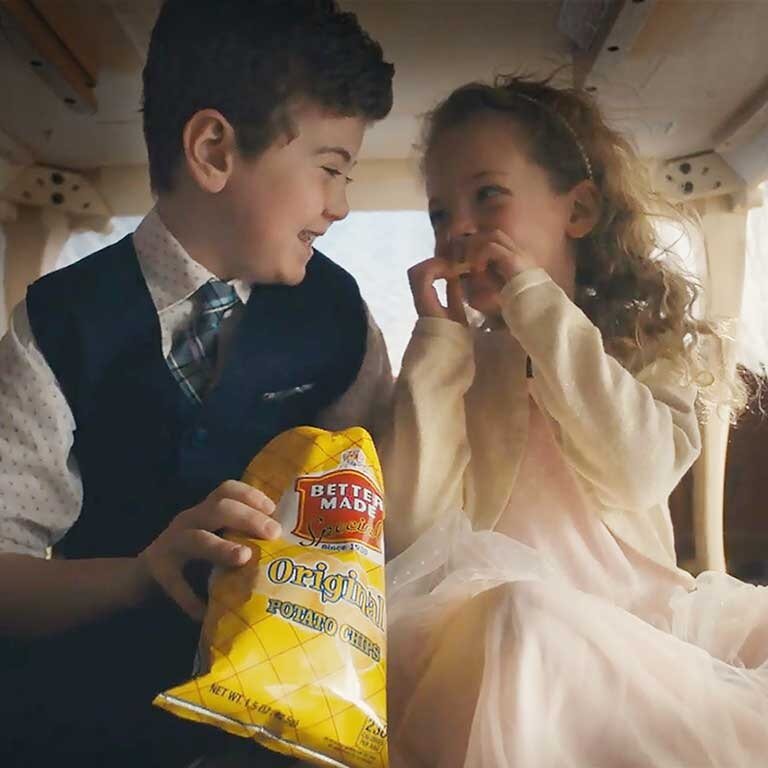 Two children under a kitchen table eating Better Made chips