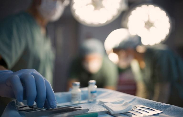 A picture of a surgeon reaching for a medical instrument in an operating room. 