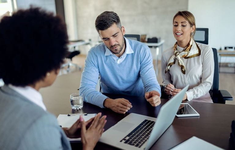 Business professionals having a meeting together while looking at a laptop computer screen