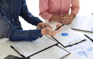 Reports laid out on a table in front of two businesspeople.