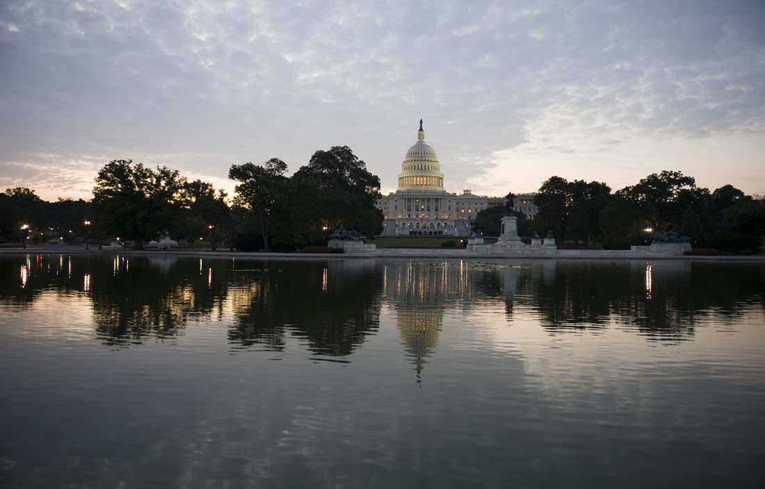 U.S. Capitol building reflecting in water at dusk.