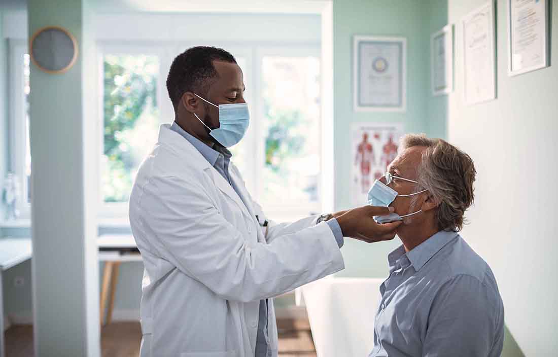 Doctor wearing a mask and examining their patient.