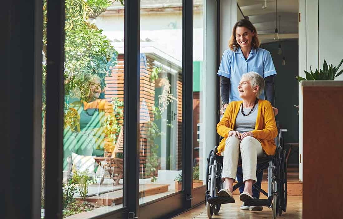 Senior care worker pushing an elderly senior in a wheel chair