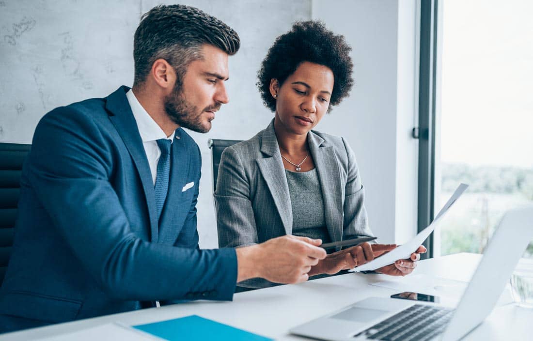 Two business professionals engaged in a lively discussion about GASB updates during a meeting in a modern office setting.