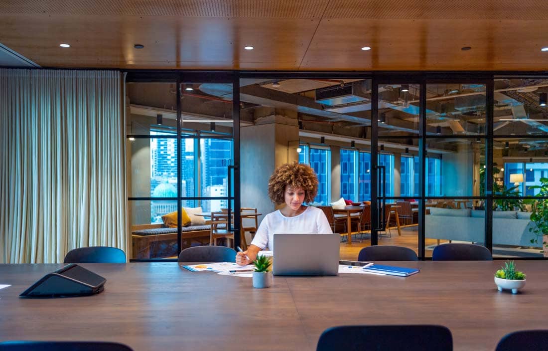 Internal audit professional on their laptop in an empty conference room.