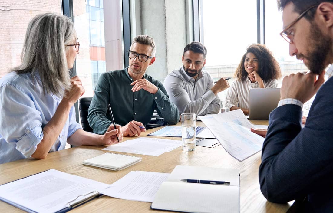 Group of insurance professionals gathered around a conference room table.
