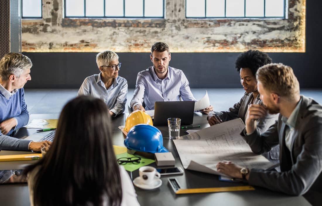 Real estate and construction professionals gathered around a table in a meeting.