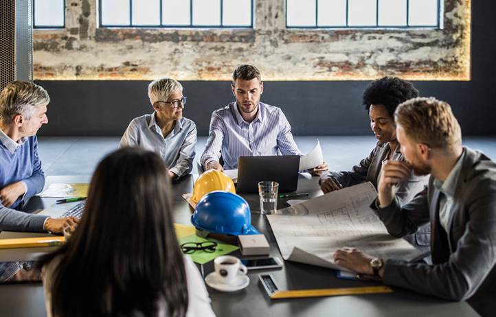 Real estate and construction professionals gathered around a table in a meeting.