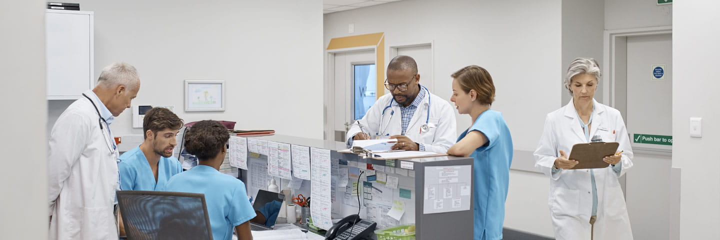 Doctors and nurses gathered around a nurse's station.