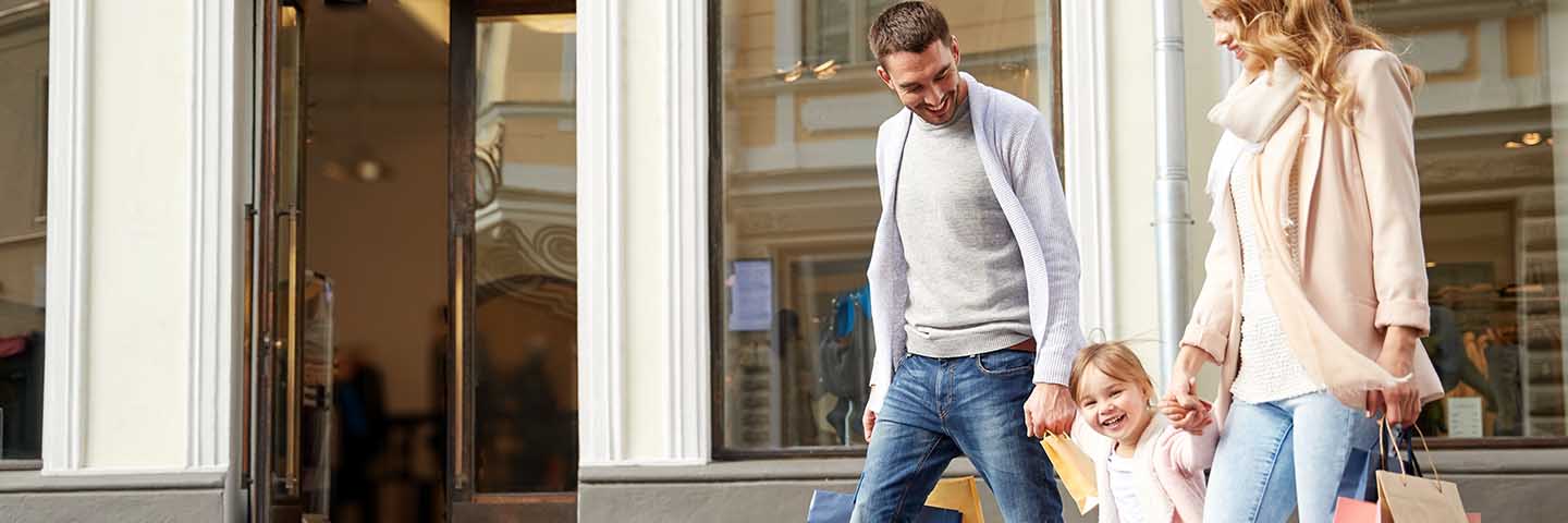 Couple holding their toddler's hand while walking out of a store.