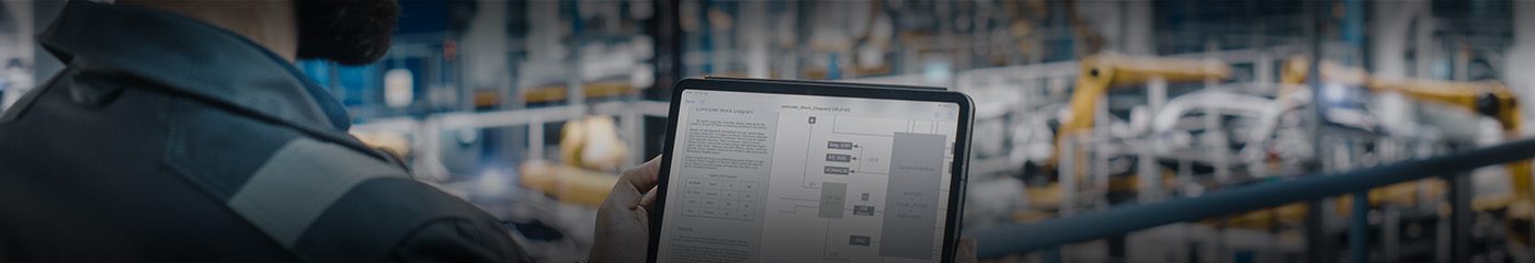 Manufacturing professional in a warehouse using a handheld tablet device.