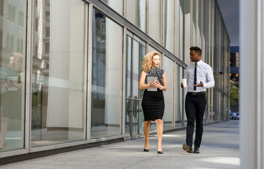 Two employee benefit professionals talking outside of an office.