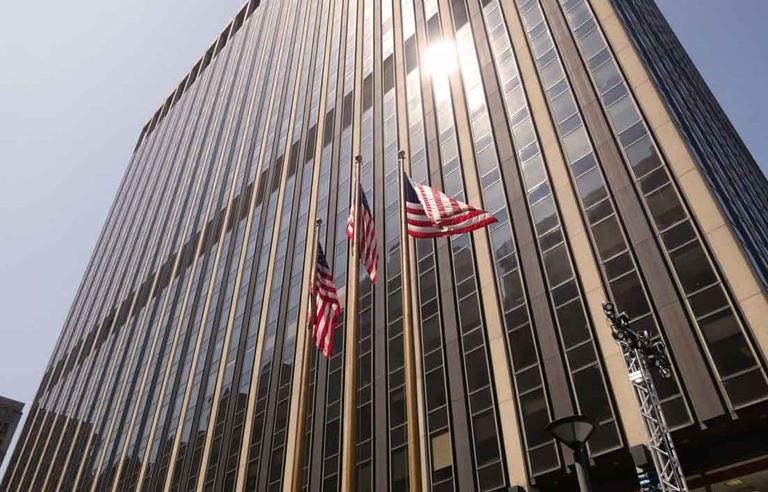 Photo of skyscraper with American flags out front.