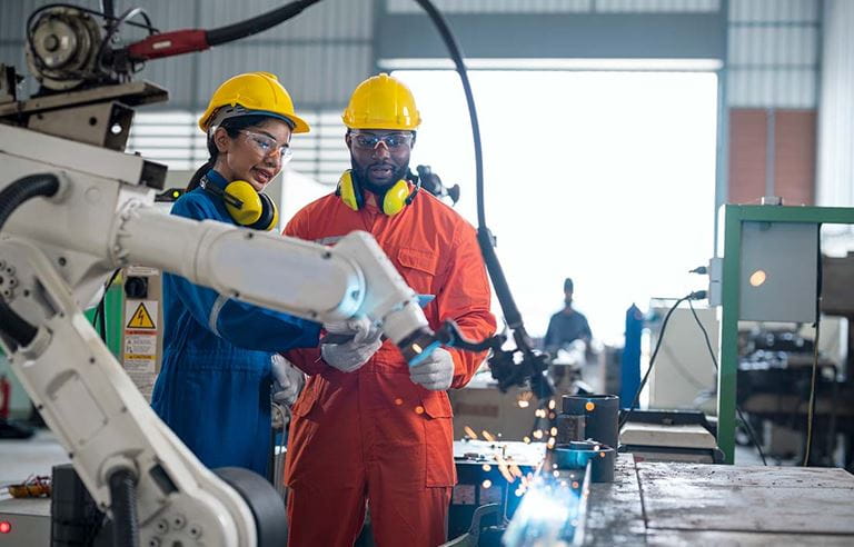 Factory workers nearby a robotic machine.