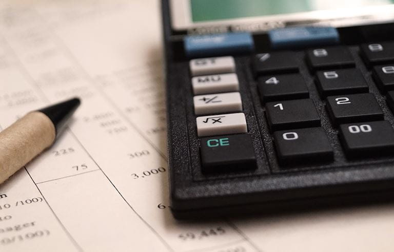 Calculator and pen laying on top of paperwork. 