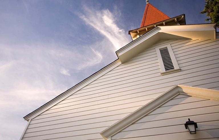 Photo looking up at a church building with a daytime sky in the background. 