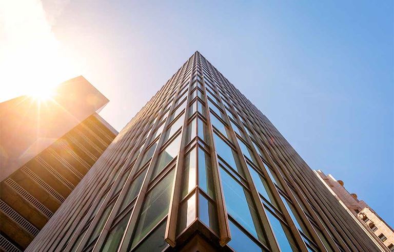 Viewpoint image, looking up at the sky and top of a tall glass-windowed building.