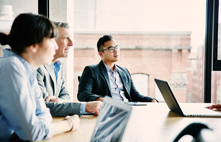 Business people sitting around a table looking at a presentation. 