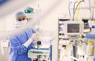 Picture of a female nurse moving medical equipment in an operating room. 