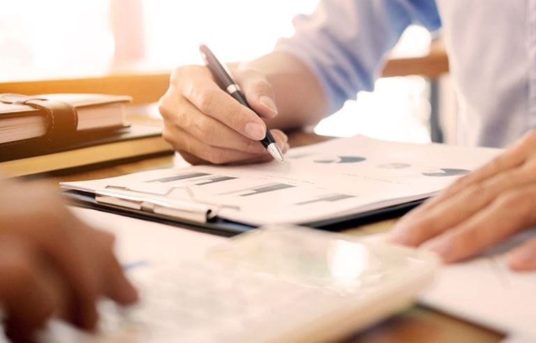 Close-up of a person's hand holding a pen and writing notes.