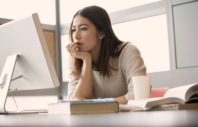 Woman sitting at a computer desk researching retirement savings plans. 