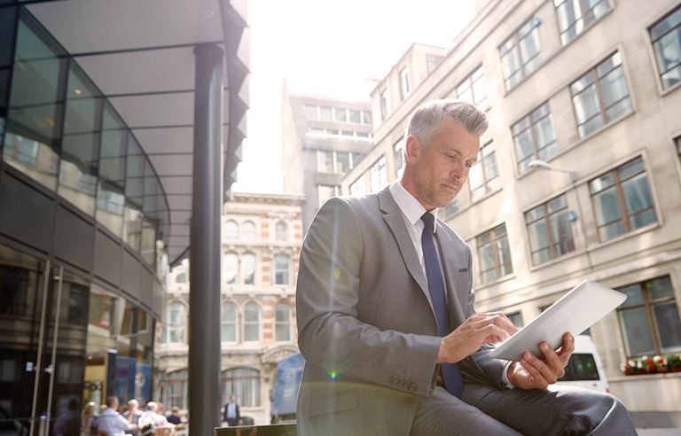 Image of man using iPad while sitting outside