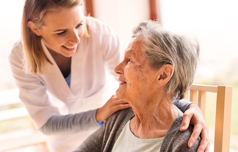 A nurse checking on an elderly woman.