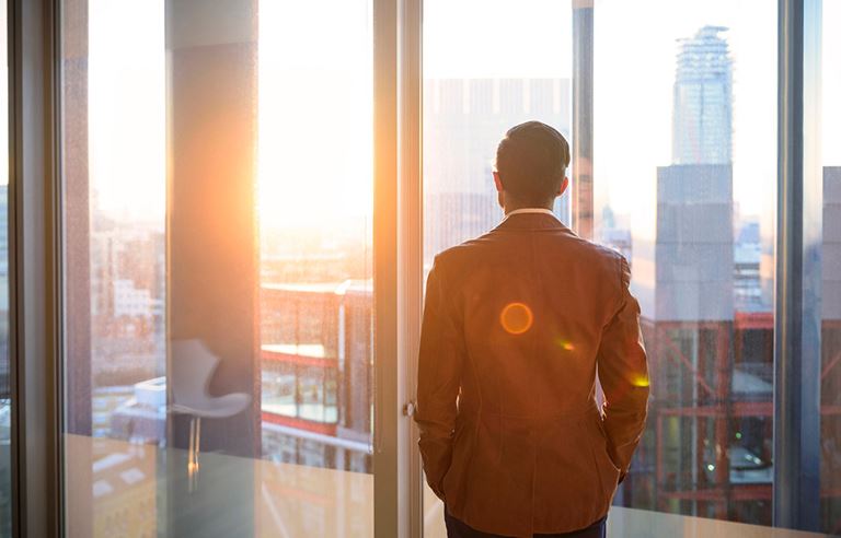 Image of business man looking office window.