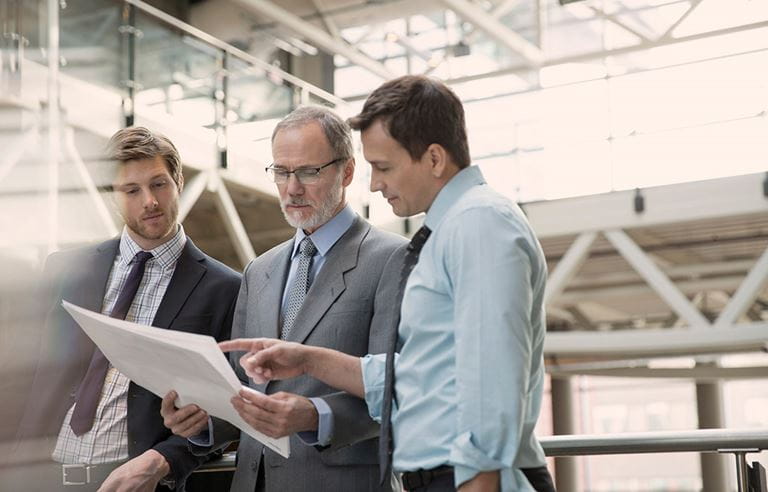 three business men looking at paper