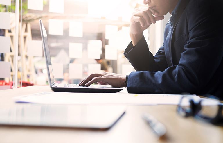 Man researching due diligence phase on laptop