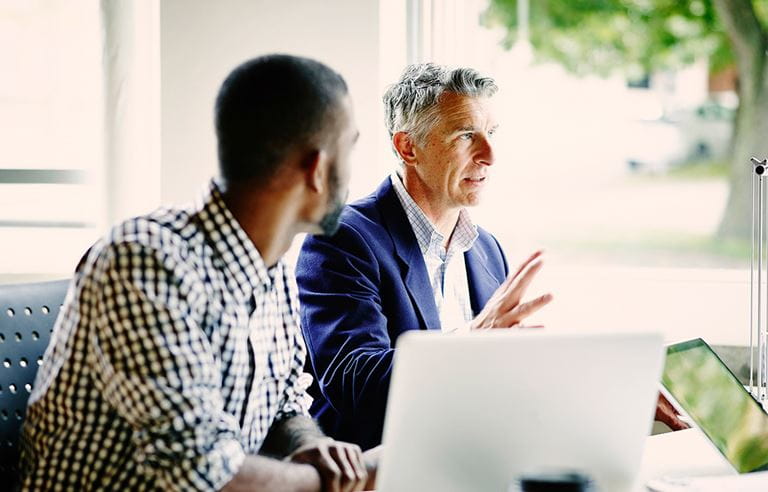 Two people talking over a computer