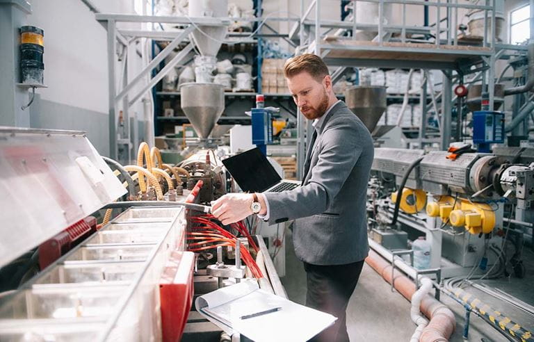 Business professional inspecting a factory floor.