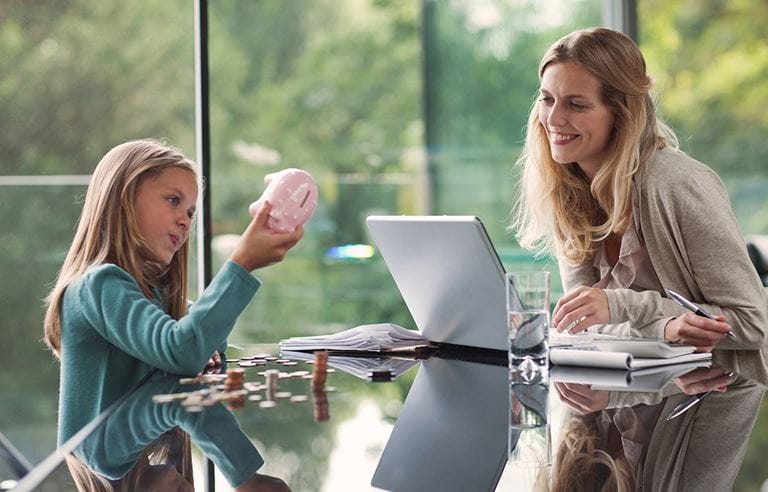 A mom and daughter sitting at a table, counting change