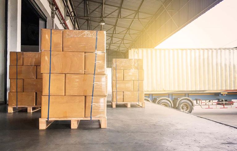 Loading dock with cardboard boxes sitting on wooden pallets. 