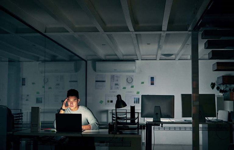 man sitting in dark at a desk