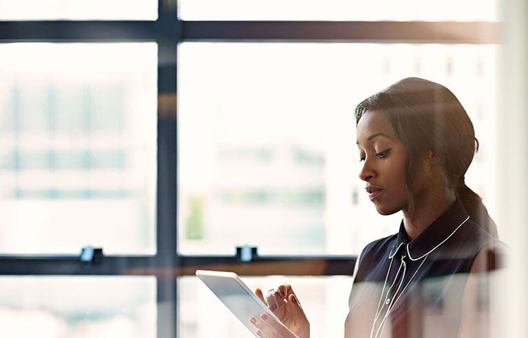 Young businesswoman reading about the CARES Act on a tablet hand-held device.