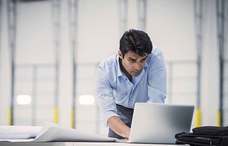 Construction foreman using a laptop computer at a desk.