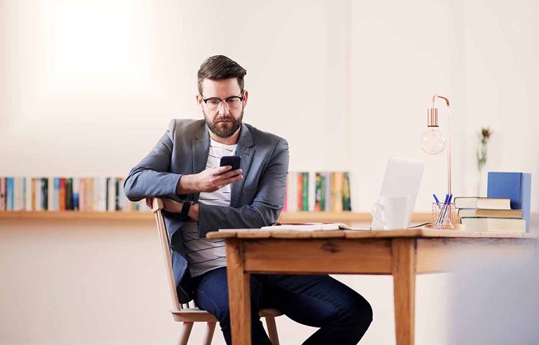 Man sitting at a table, looking at his cellphone