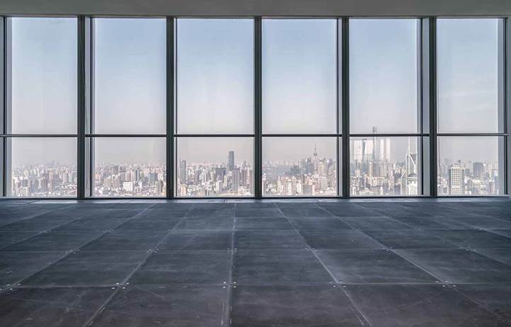 Empty room with floor to ceiling glass windows looking out of a high rise building