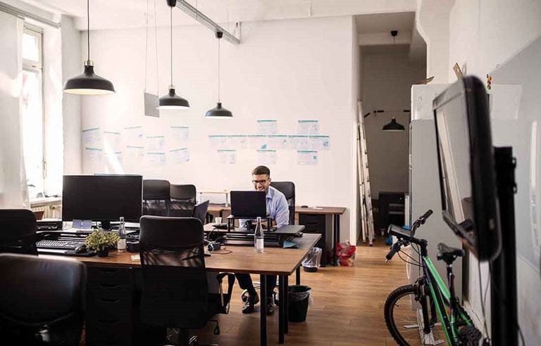 Man working in a modern looking office working at his desk alone.