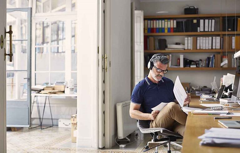 Man sitting in chair in his home office reviewing documents.