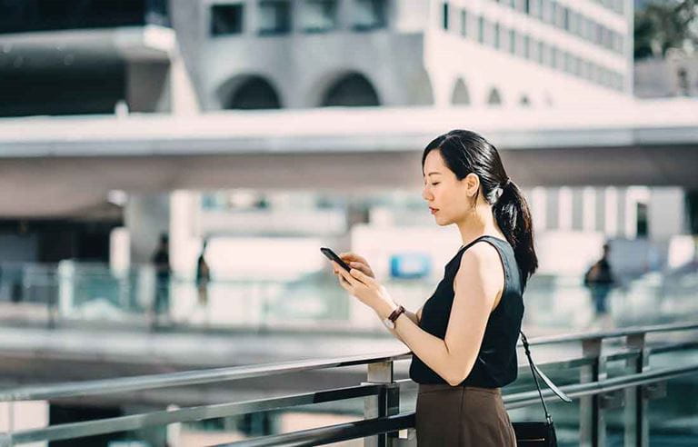 Businesswoman in an city checking her cell phone.